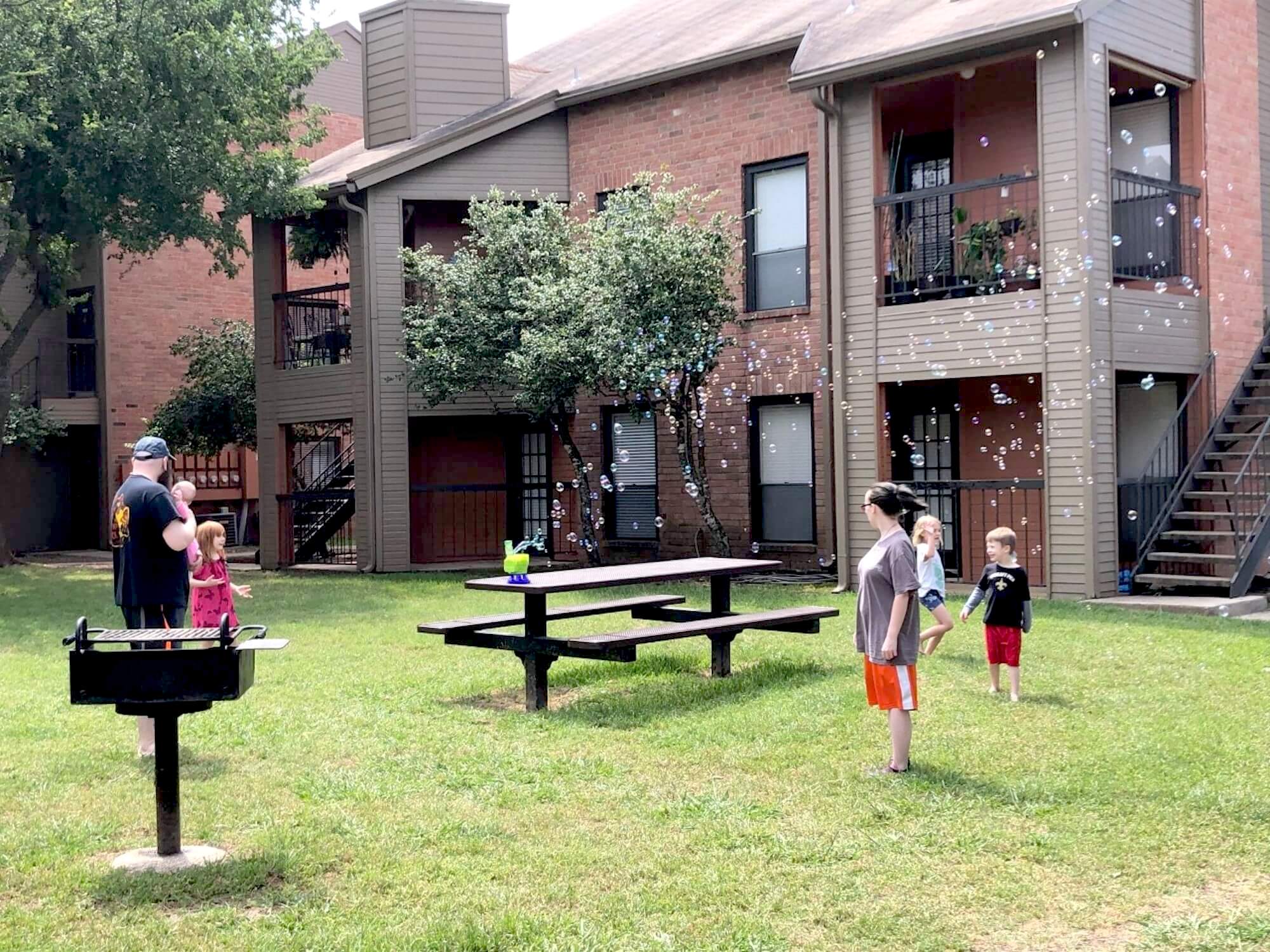 A family plays outside at the Arbors at Boerne Apartments.